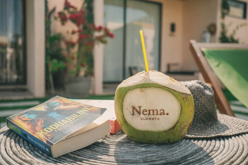 A coconut, a good book and a straw hat by the pool
