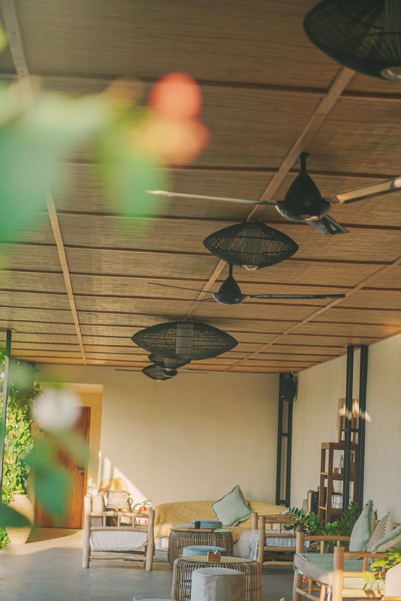 The covered common area at Nema with rattan lamps, sofas and the garden beyond